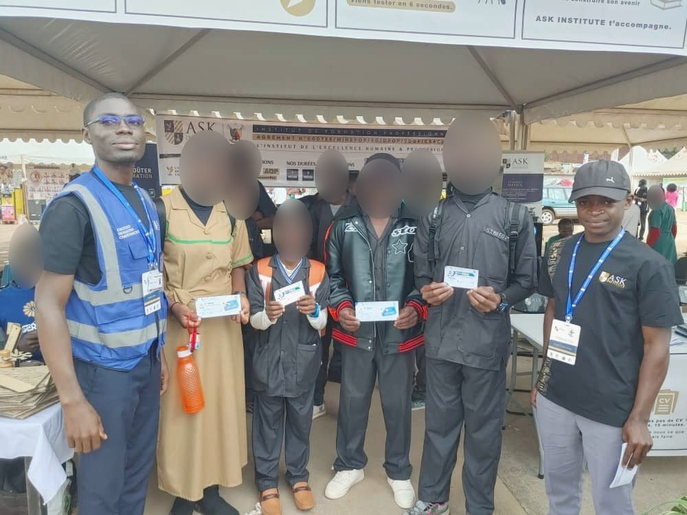 Sur le stand de ASK au CAMBE Ouest 2026, cinq jeunes visiteurs montrent la carte qu’ils tiennent en main, entourés de deux membres de l’équipe de ASK.