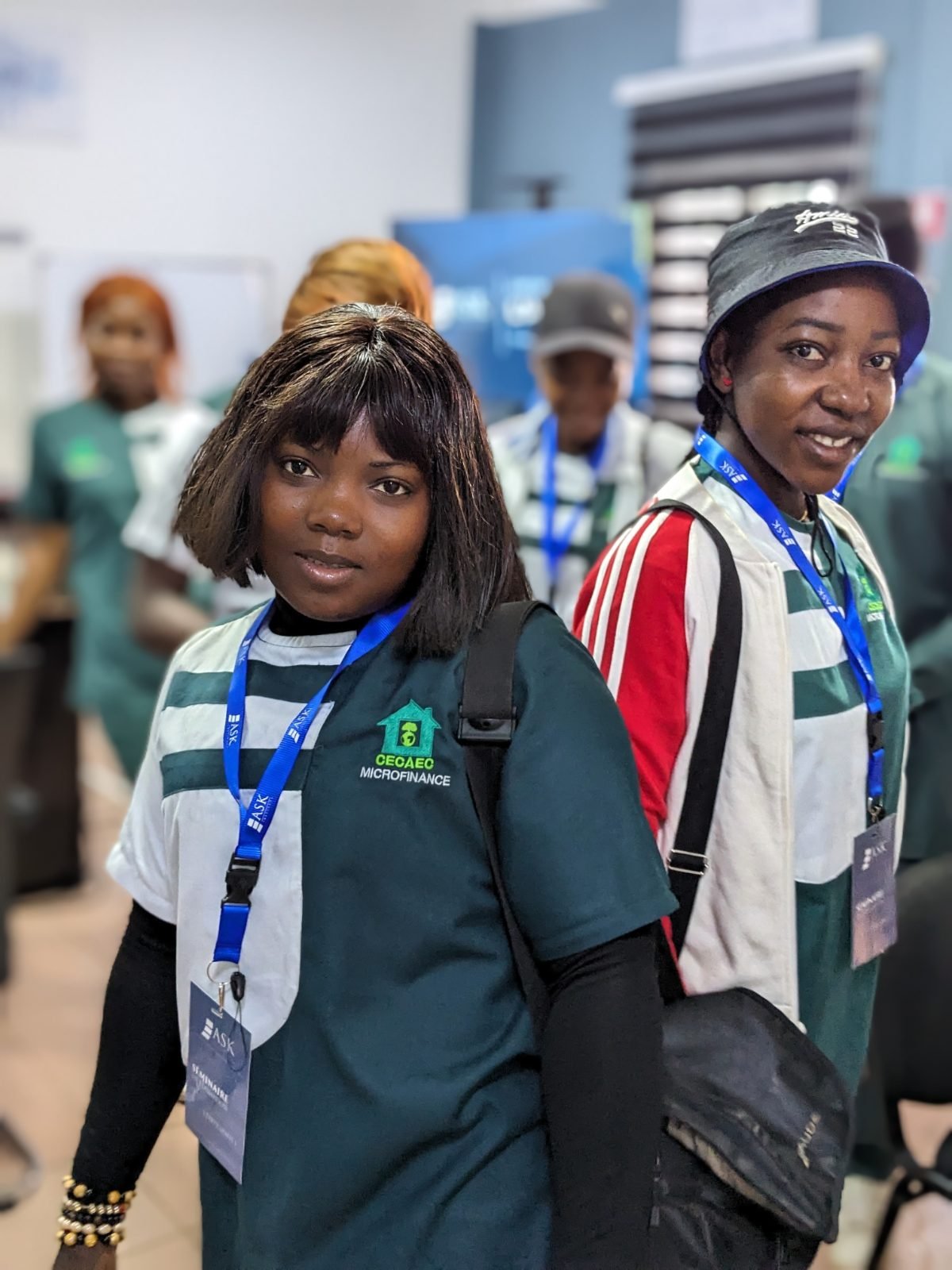 Deux participantes de la CECAEC COOP-CA, en tenue de l’institution et badge de ASK Institute au cou, sourient à l’objectif.