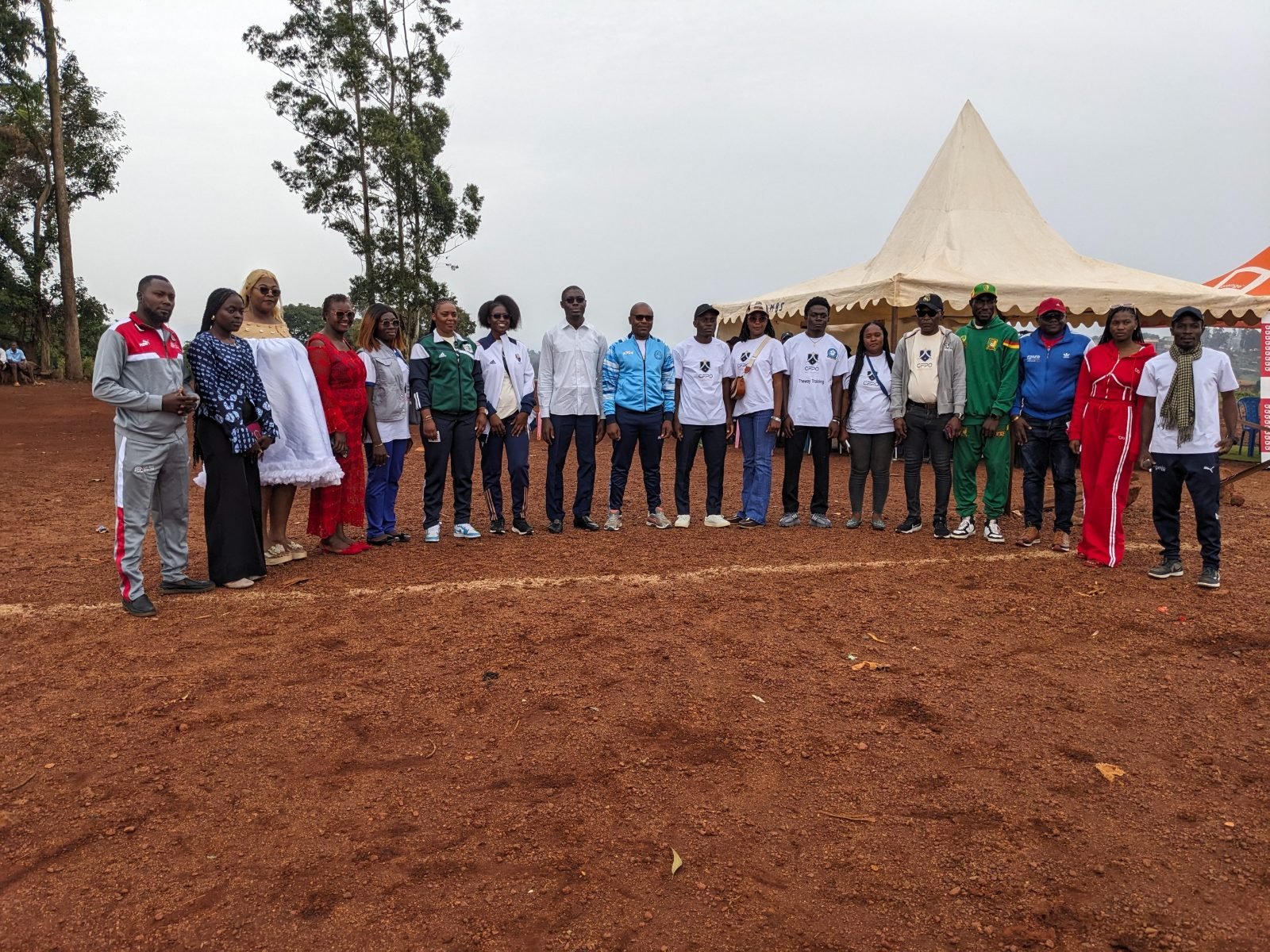 Officiels, organisateurs et participants alignés sur le terrain, devant les tentes de la compétition.