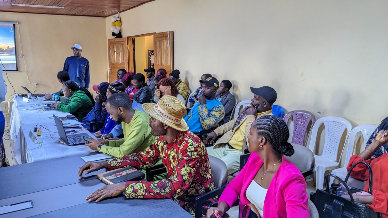 Des participants assis le long des tables suivent les échanges.