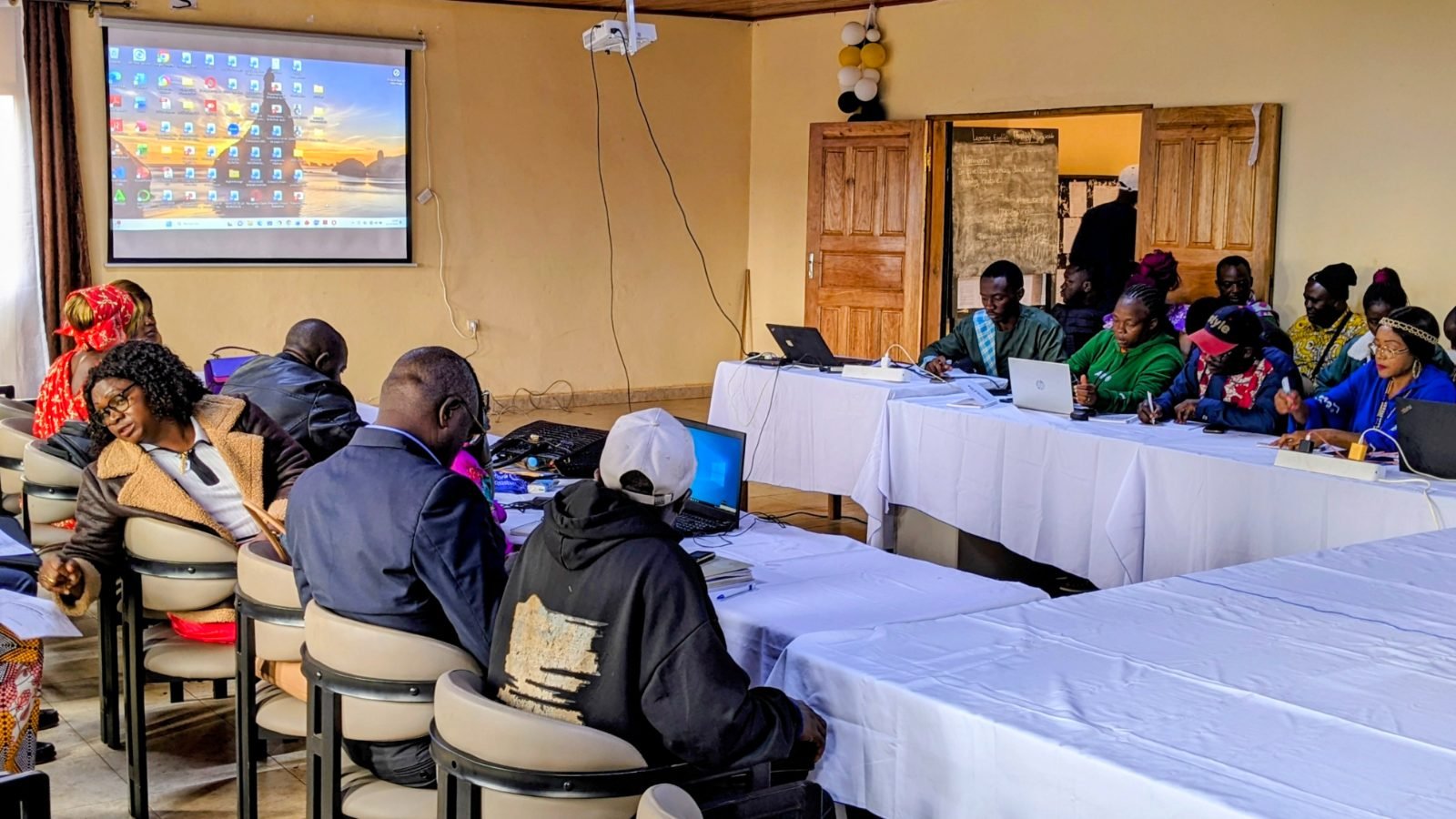 Les participants de la session, installés autour des tables, face à l’écran de projection.
