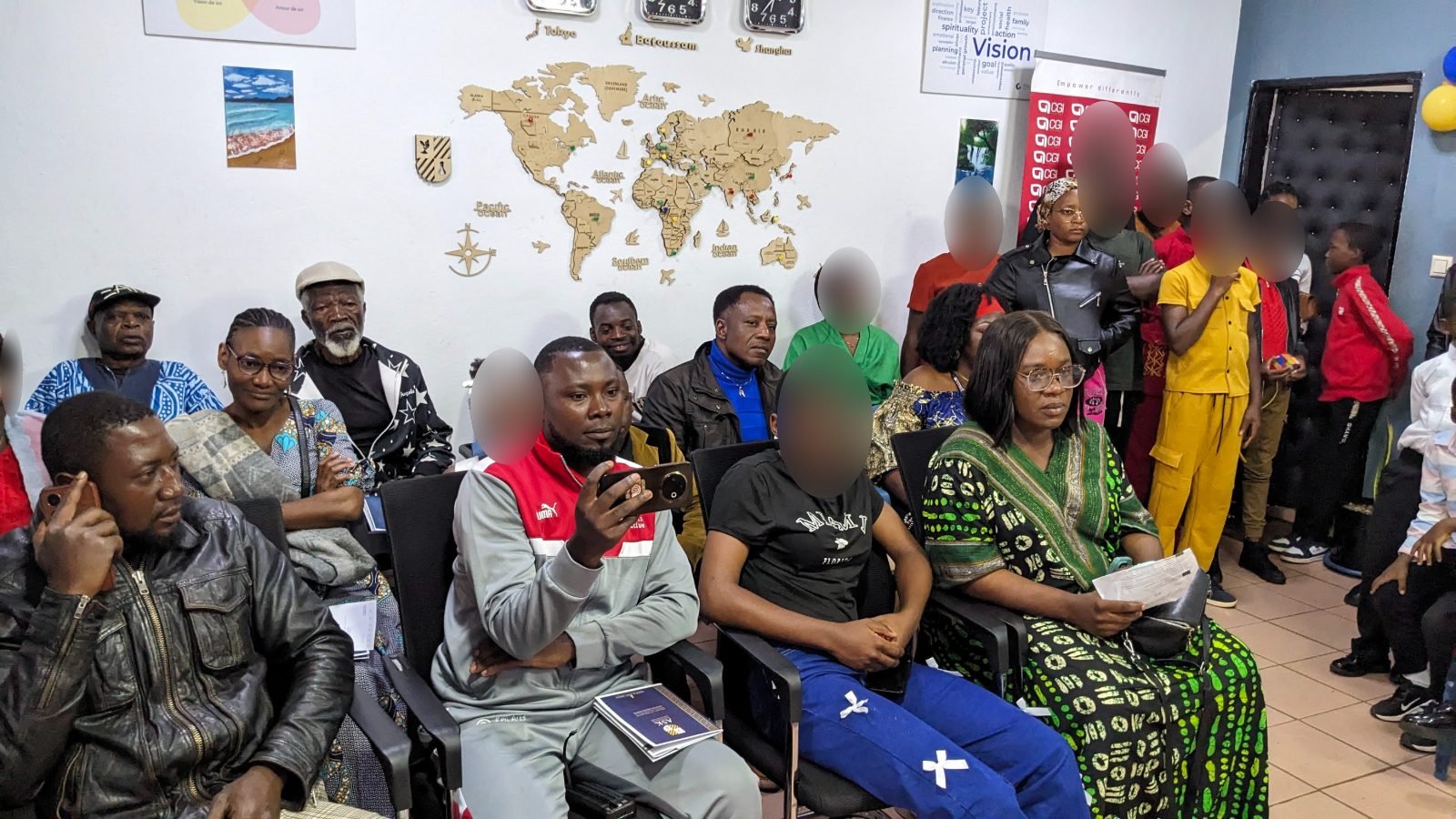 Parents, enfants et invités réunis dans une salle du campus décorée d’une carte du monde, pendant la cérémonie.