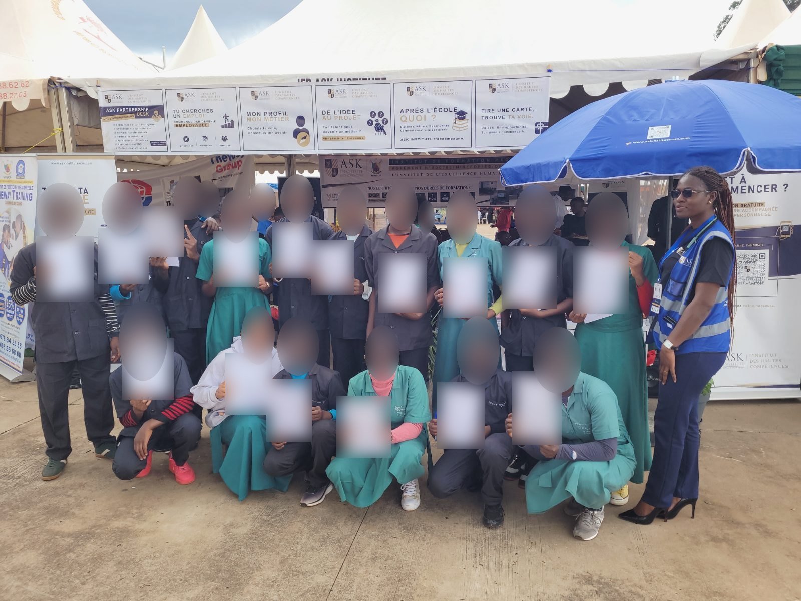 Devant le stand de ASK au CAMBE Ouest 2026, un groupe d’élèves en blouse présente son certificat de participation, aux côtés d’une membre de l’équipe de ASK en gilet.