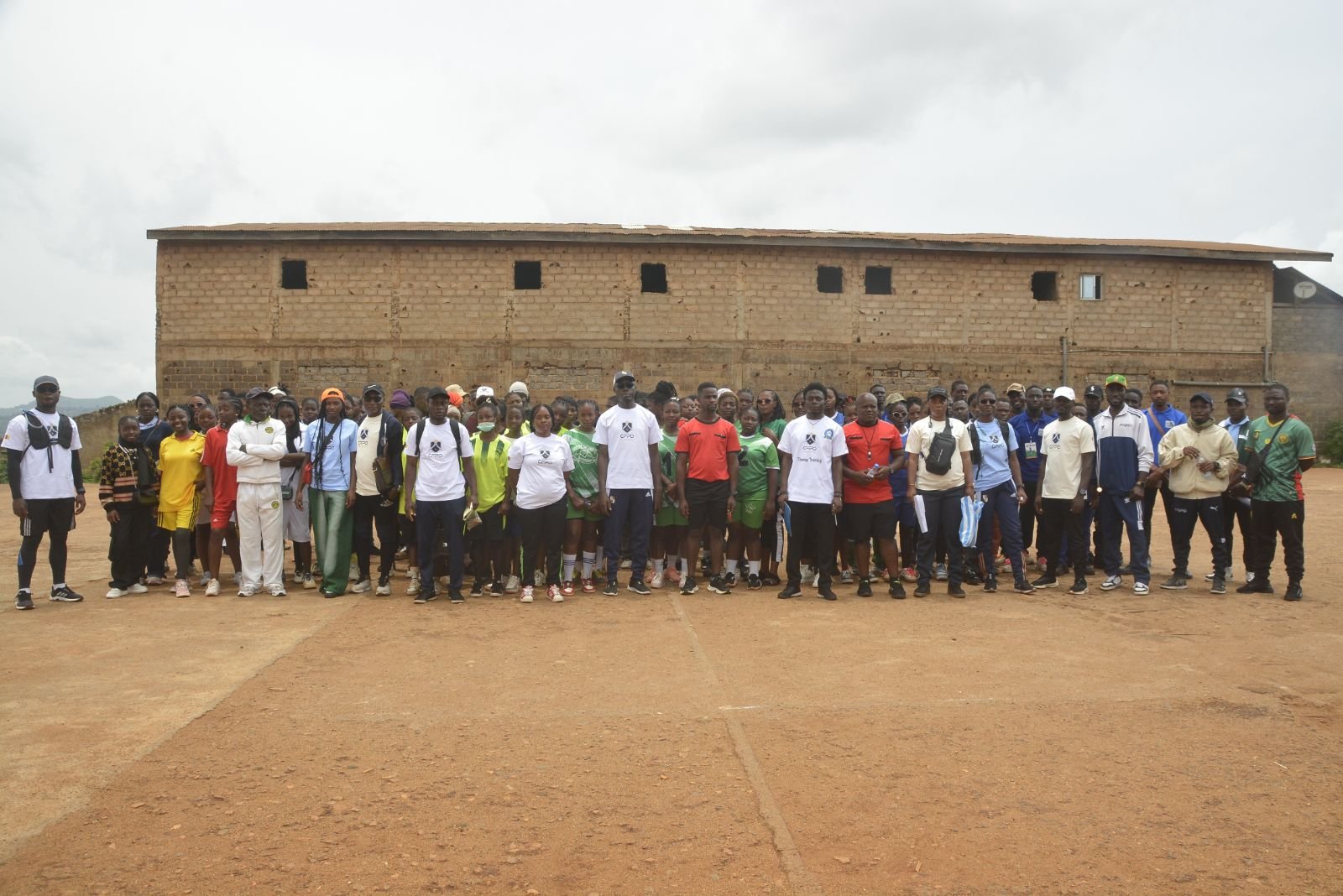 Photo de groupe des participants, alignés sur le terrain